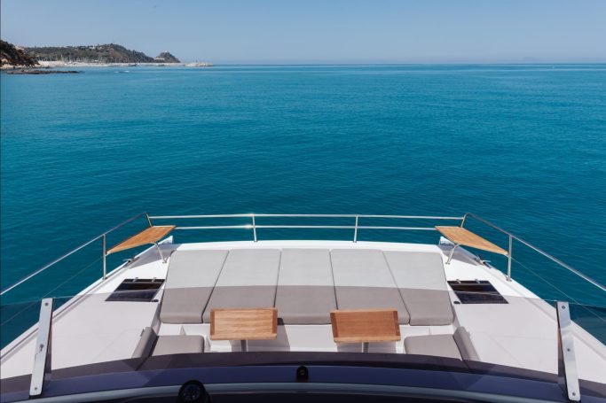 Catamarano Prua Prua di un yacht moderno con lettini su un mare turchese e cielo sereno.