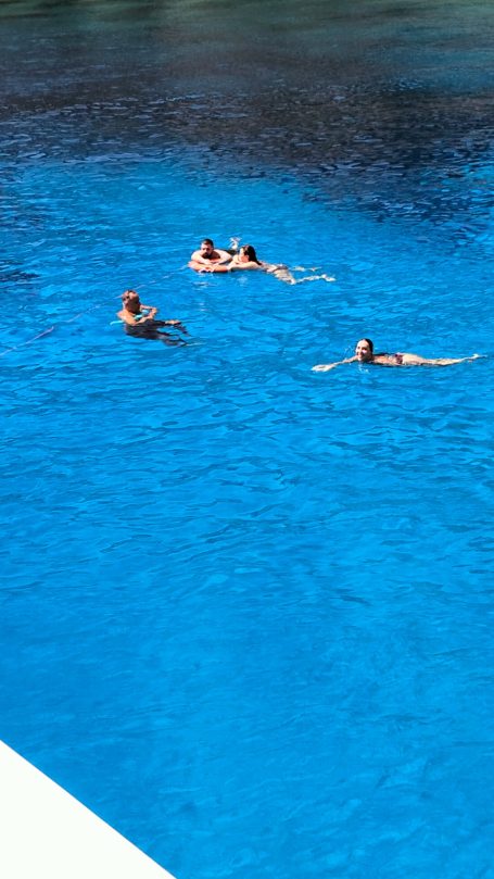 Favignana sosta bagno Due persone nuotano in una piscina blu, circondate da acqua limpida.