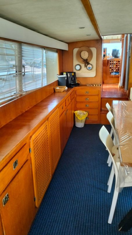 Salotto Shalimar IV Interno di una barca, con armadietti in legno e tavolo da pranzo.