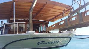 Caicco "Poppa" Barca a motore con copertura in legno attraccata vicino a una spiaggia tropicale.