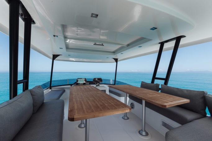 Catamarano Flyer Spacious outdoor seating area on a boat with ocean views and wooden tables.