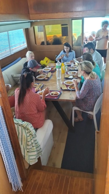 Yacht Shalimar IV Group of people gathered around a table, enjoying a meal together indoors.